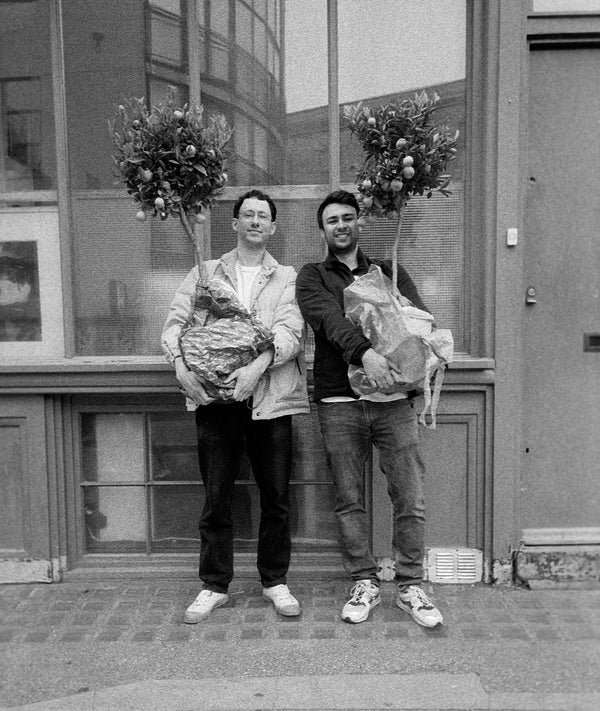 Black and white photo of the two founders holding small trees